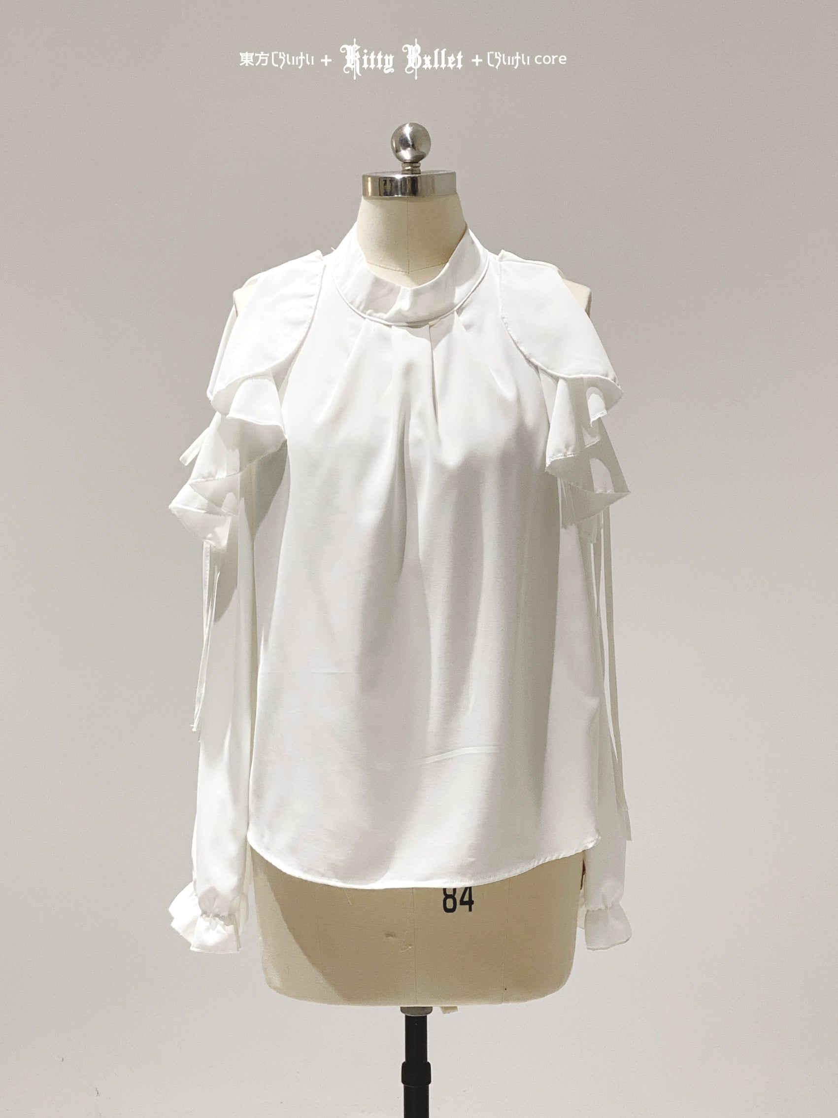White blouse with ruffled details on a mannequin against a gray background