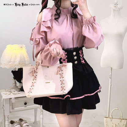Person wearing a pink blouse and black skirt holding a matching handbag in a room setting.