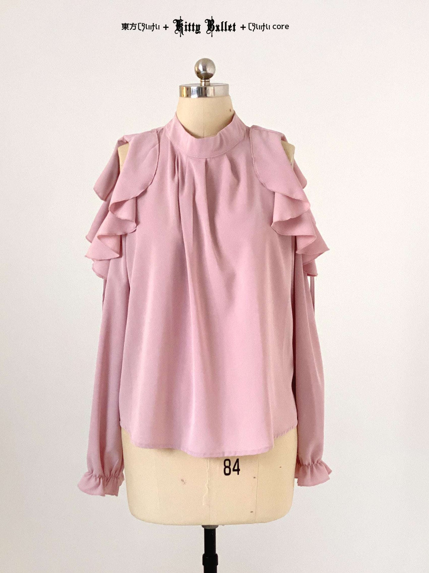 Pink blouse with ruffled shoulders on a mannequin against a white background