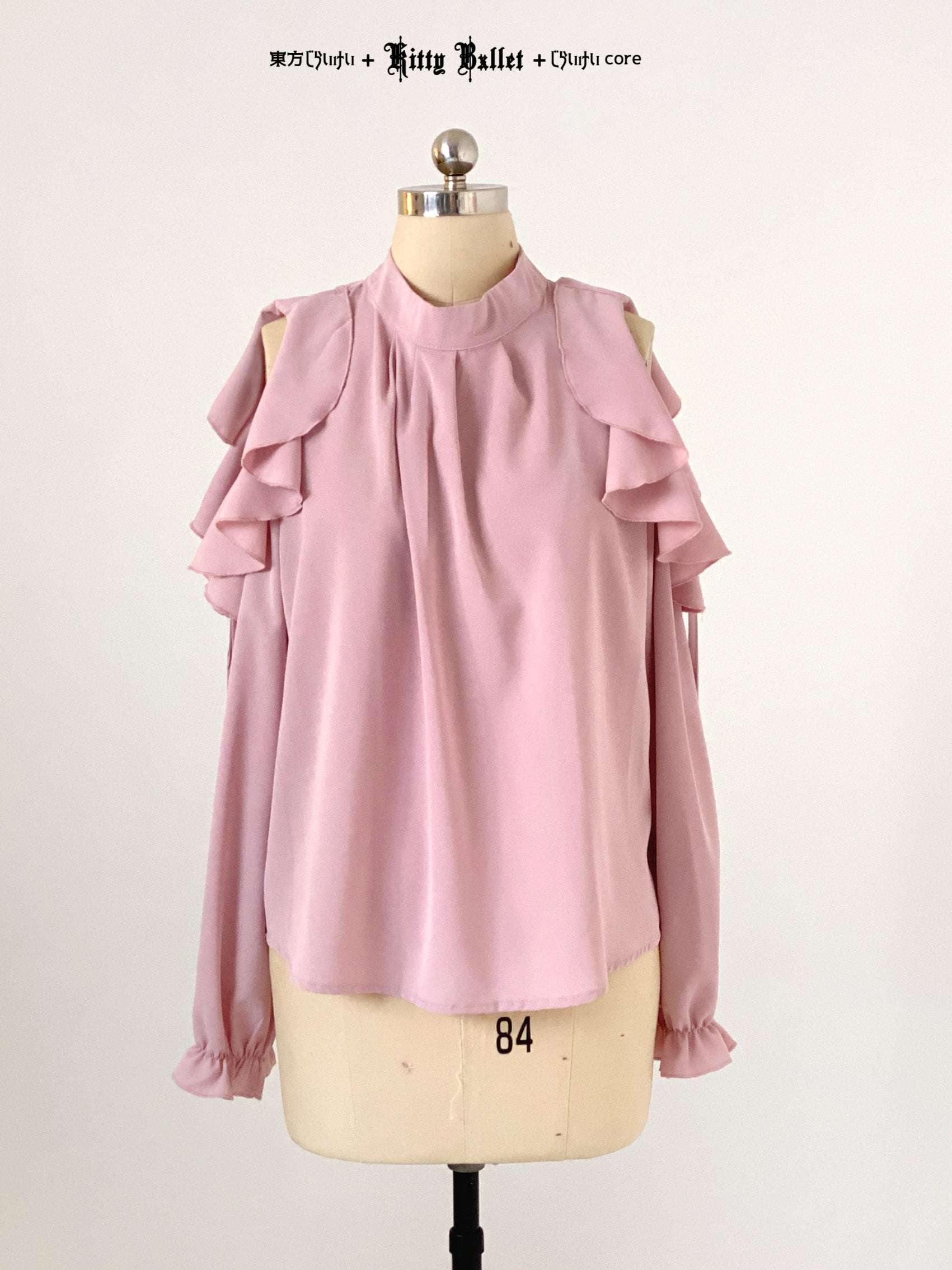 Pink blouse with ruffled shoulders on a mannequin against a white background