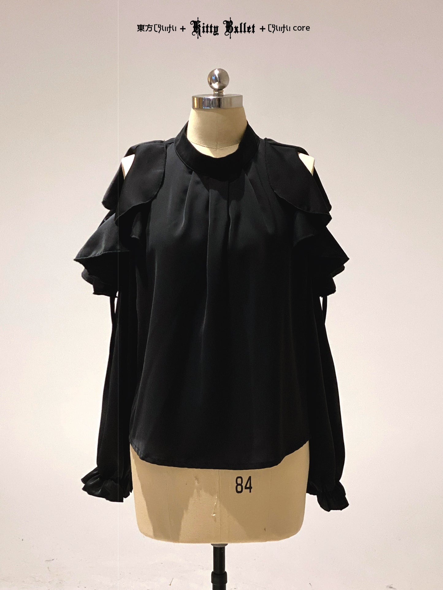 Black ruffled blouse on a mannequin with a plain background