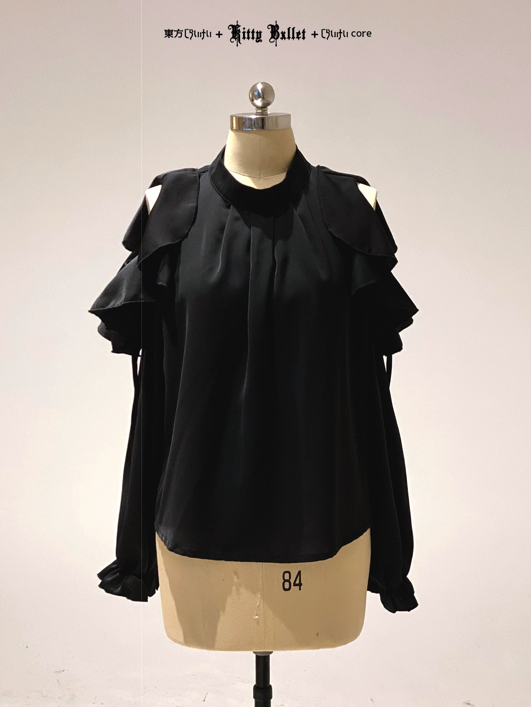 Black ruffled blouse on a mannequin with a plain background