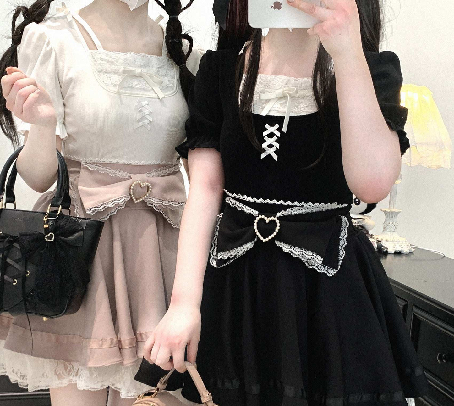 Two people wearing dresses with heart-shaped details, one in white and the other in black.