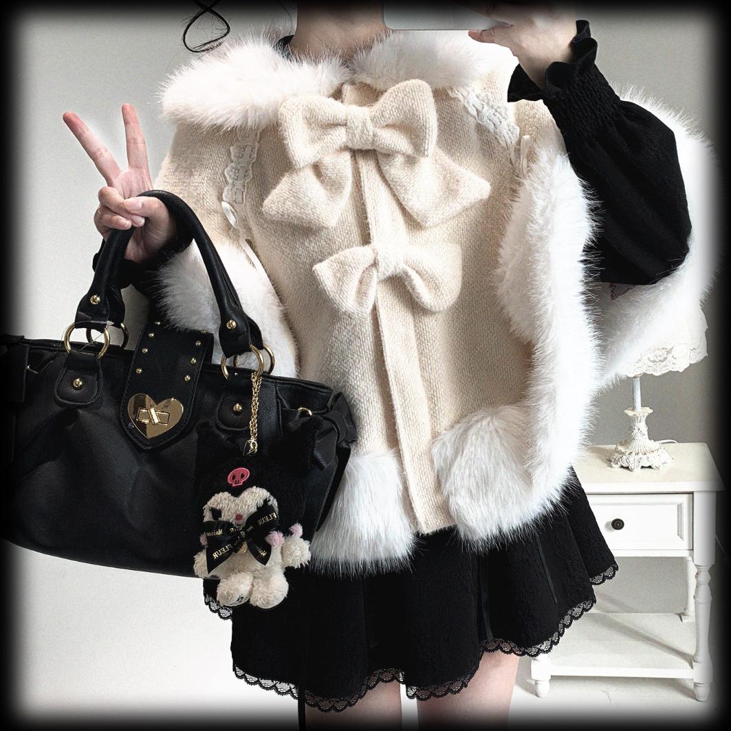 Person wearing a white fluffy coat with bow details, holding a black handbag with a small plush toy attached.