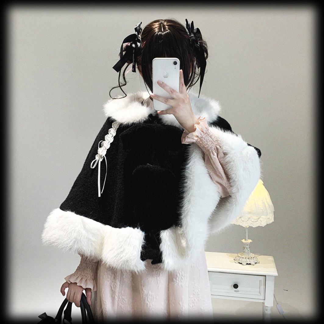 Person wearing a black and white fur-trimmed coat taking a selfie in a room.