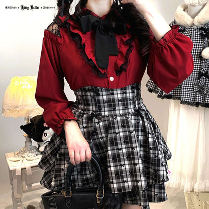 Person wearing a red blouse jirai kei style with ruffles and a black and white checkered skirt in a room setting.
