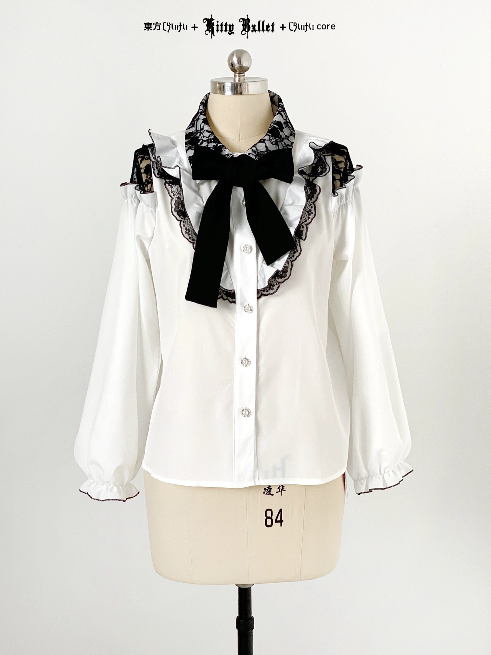 White blouse jirai kei style with black lace and bow on a mannequin against a white background