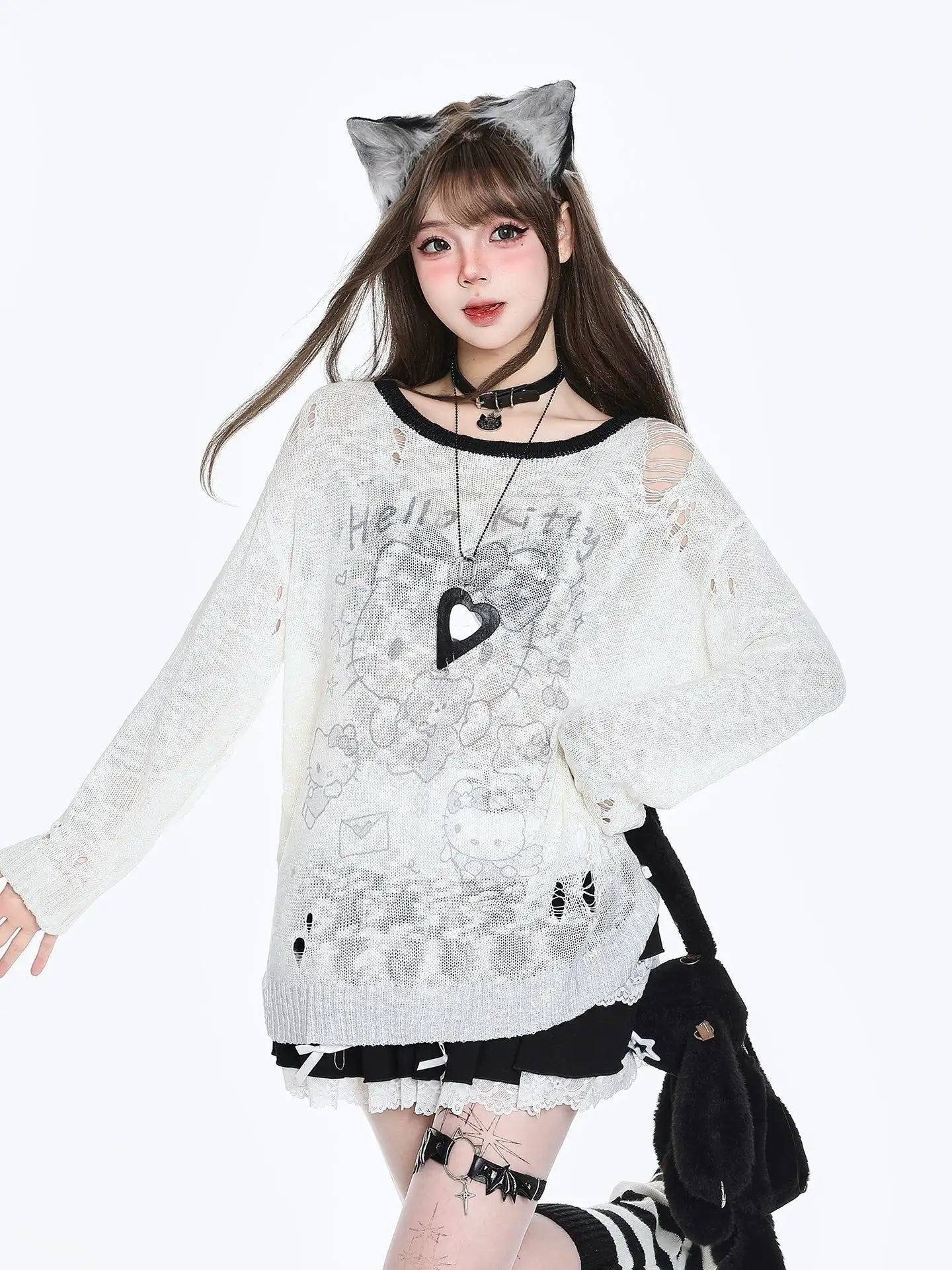 Person wearing a white sweater with black heart design, cat ears, and holding a black bag on a white background