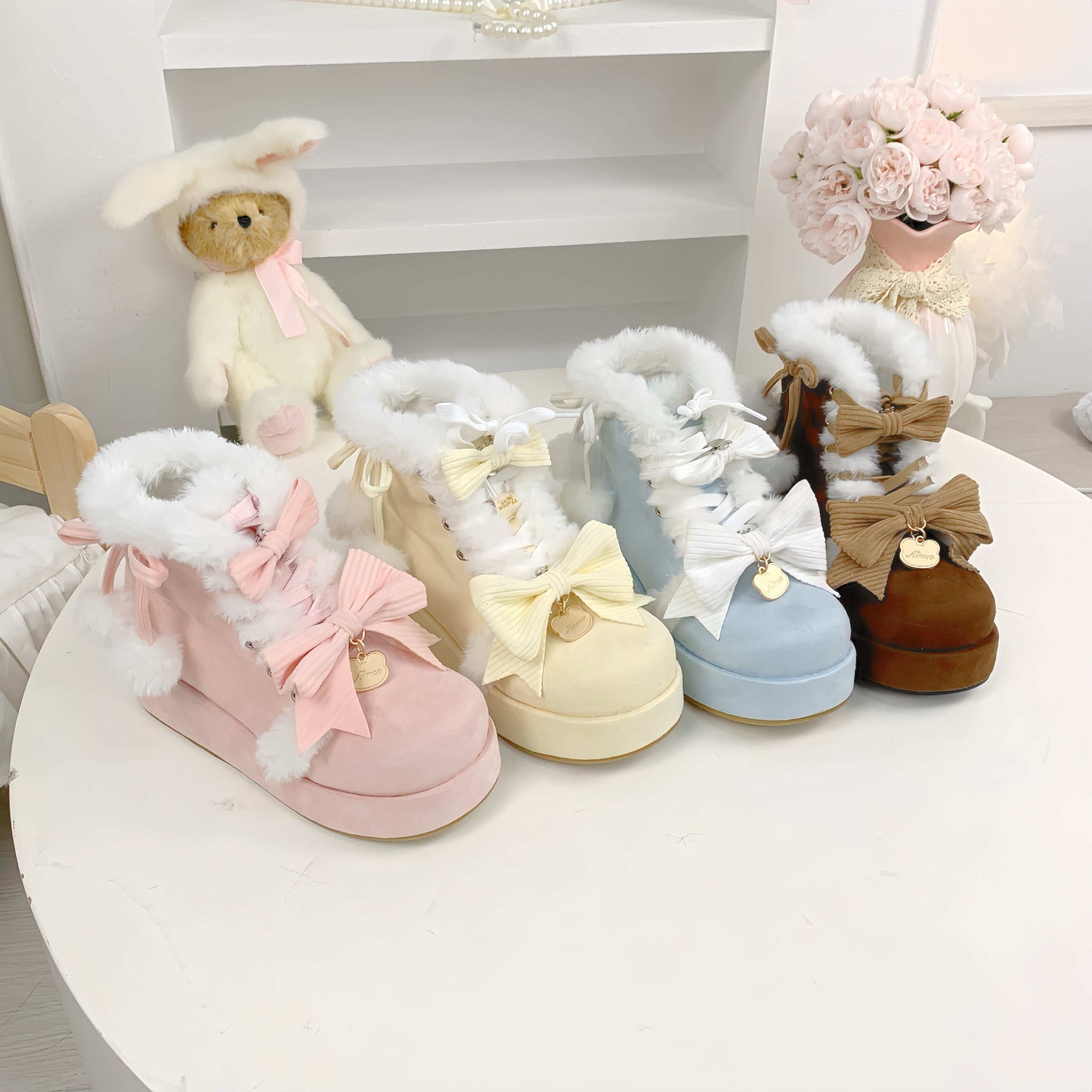 Set of pastel-colored children's boots with fluffy tops on a white surface.