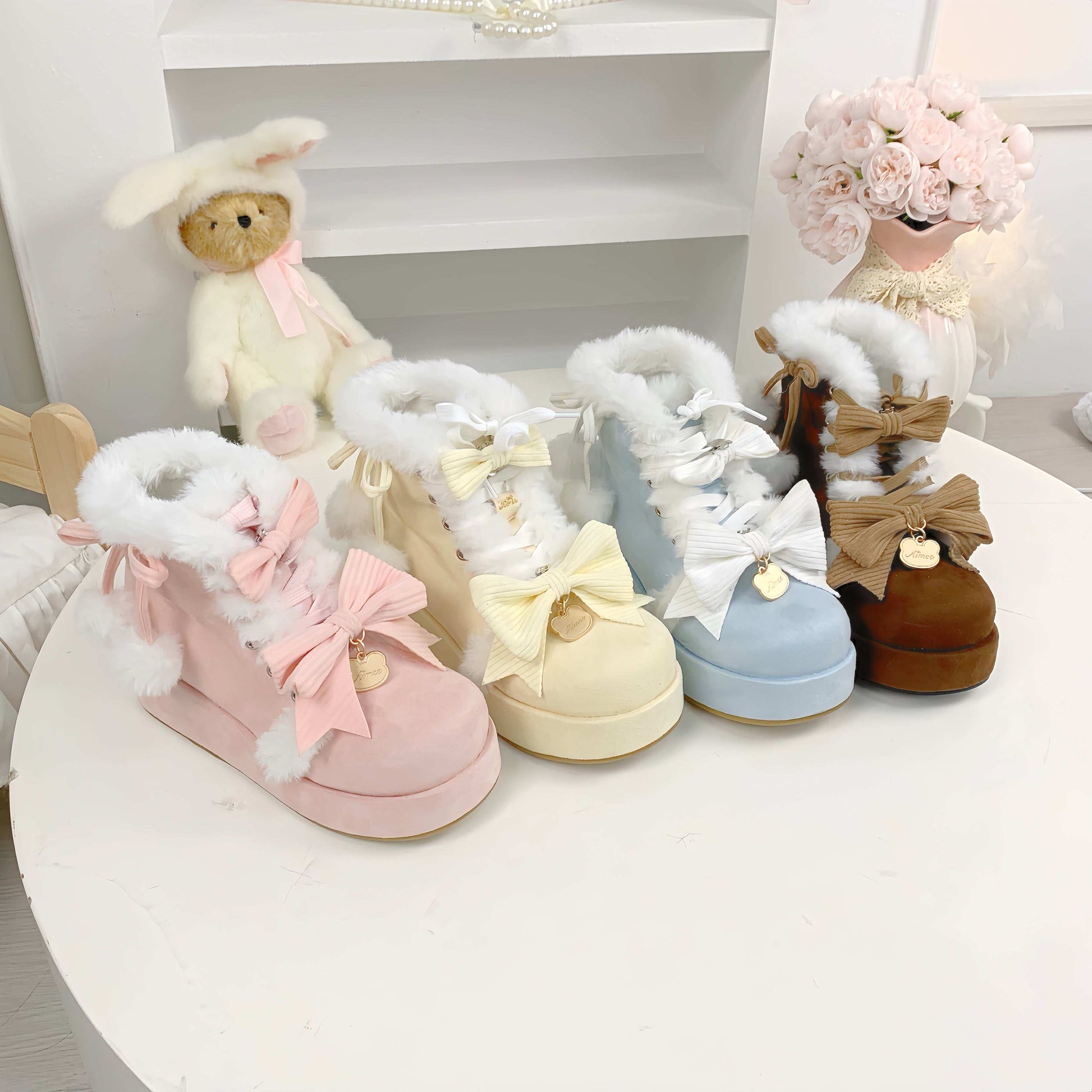 Set of pastel-colored children's boots with fluffy tops on a white surface.