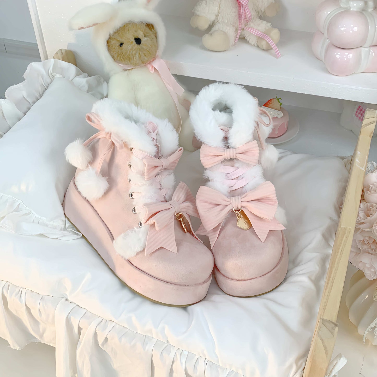 Pink winter boots with white fur and bows on a white surface with teddy bears in the background.