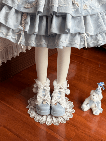 Person wearing a light blue dress with ruffles and white shoes on a wooden floor.