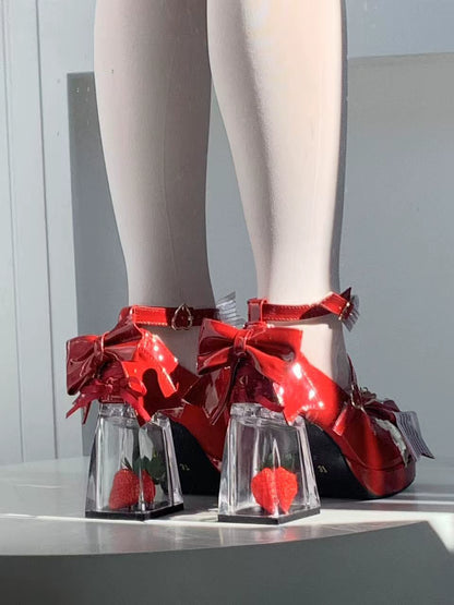 Red high-heeled shoes with clear glass platforms and red bow details on a neutral background.