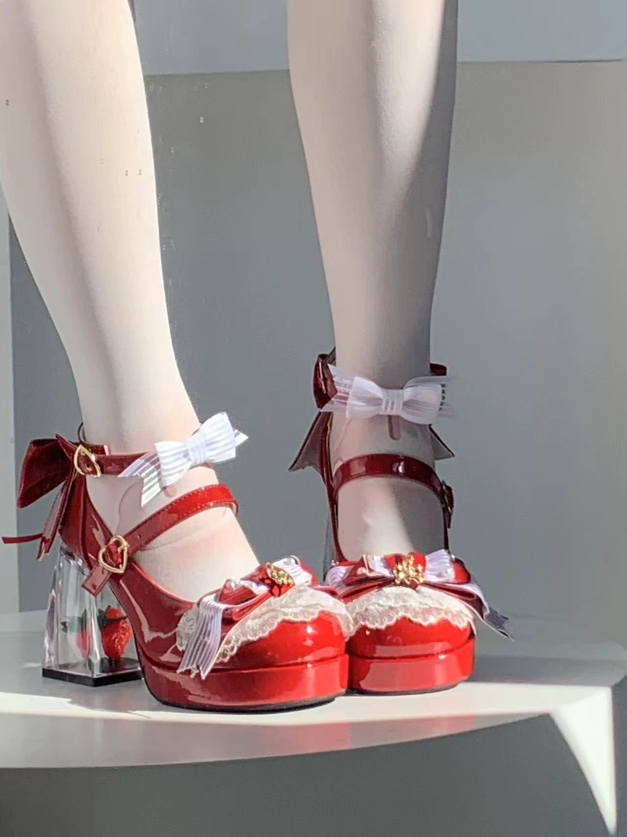 Red high-heeled shoes with decorative bows and ribbons on a neutral background