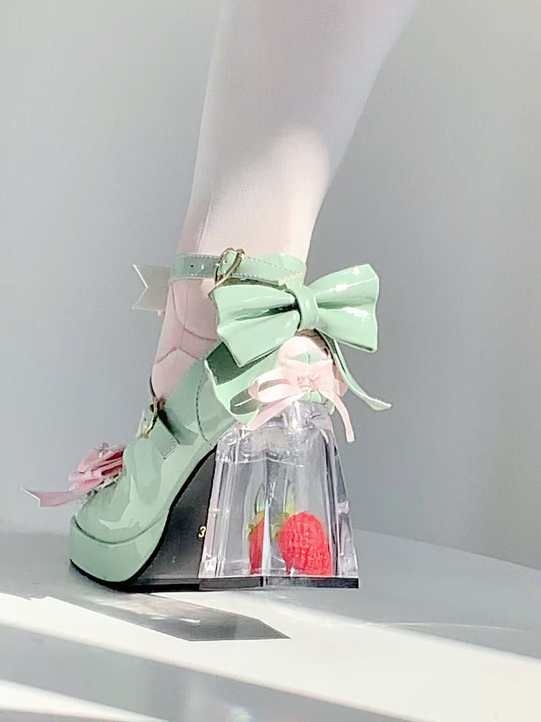 Mint green high-heeled shoes with bow detail on a white background