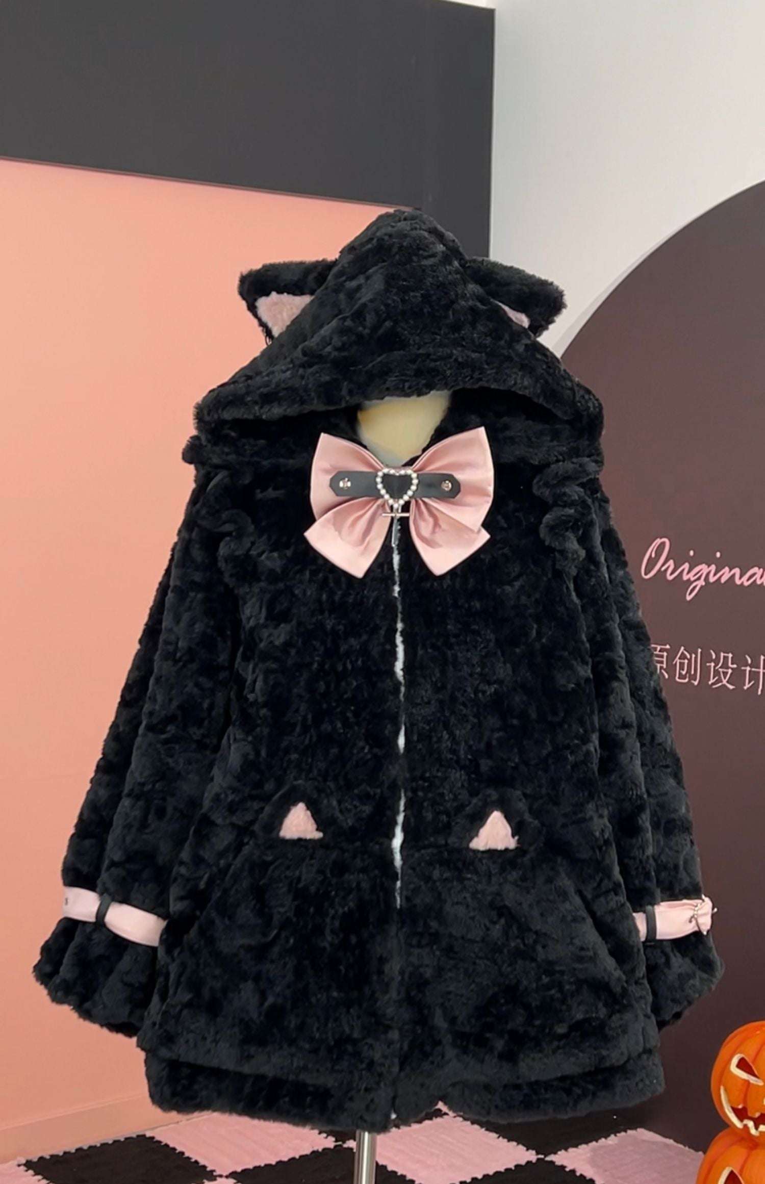 Black plush coat with pink bow on a mannequin against a colorful background