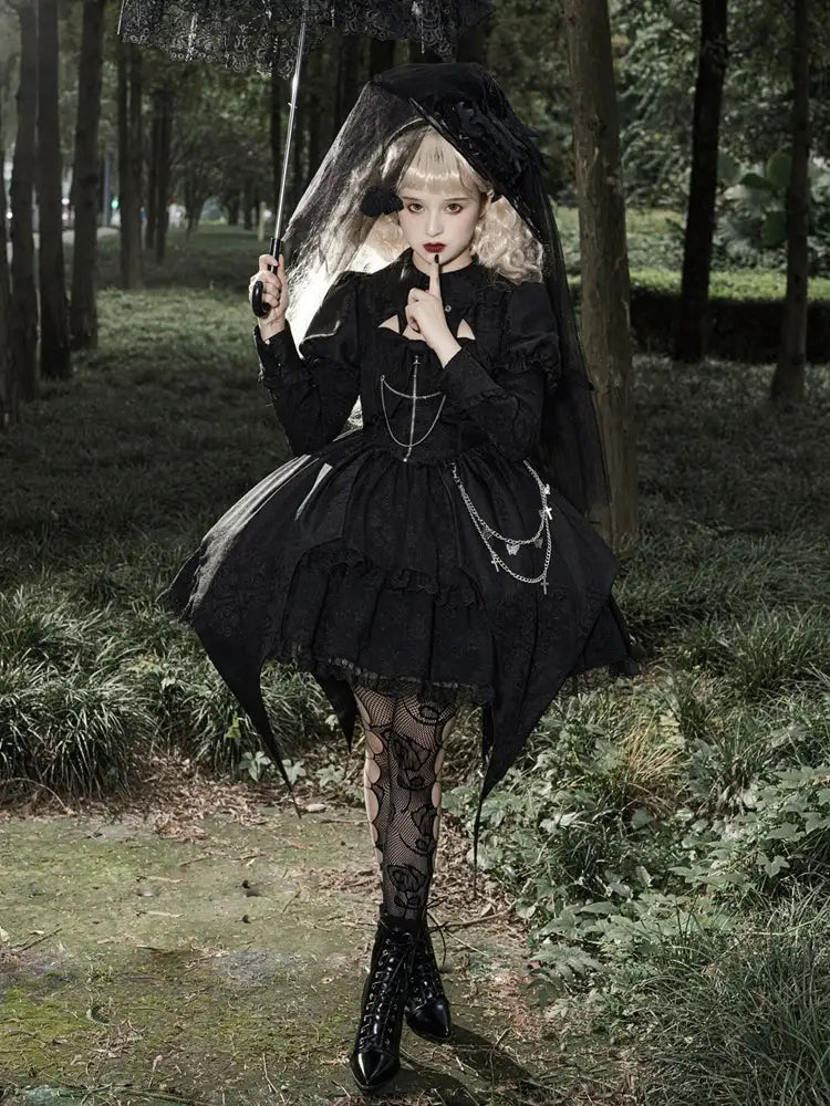 Person in a dark, gothic-style outfit with a veil walking through a forest.