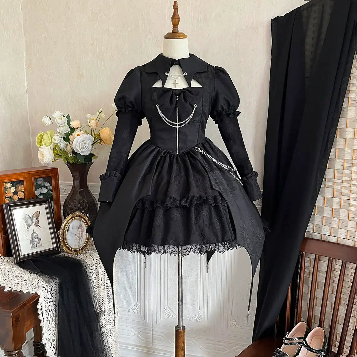 Black Lolita dress on a mannequin against a neutral wall with decorative elements.