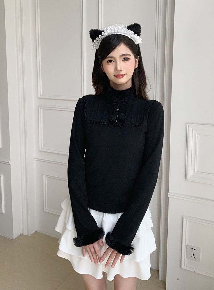 Woman wearing a black top with white ruffled skirt and cat ears headband against a white wall.