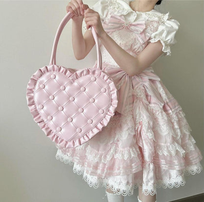 Person wearing a pink and white dress holding a pink heart-shaped bag.
