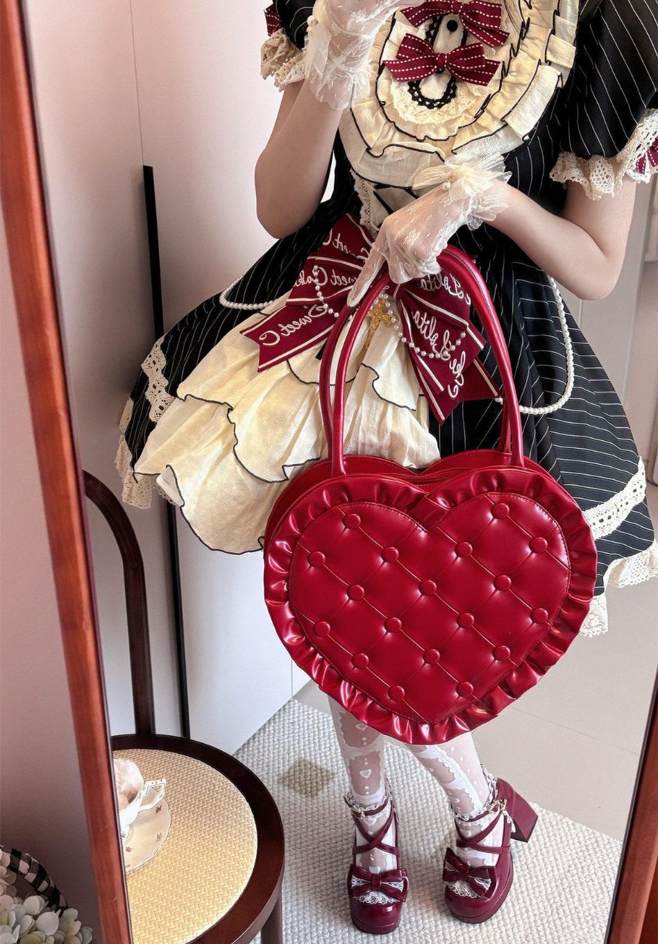 Person in a detailed outfit holding a red heart-shaped bag.