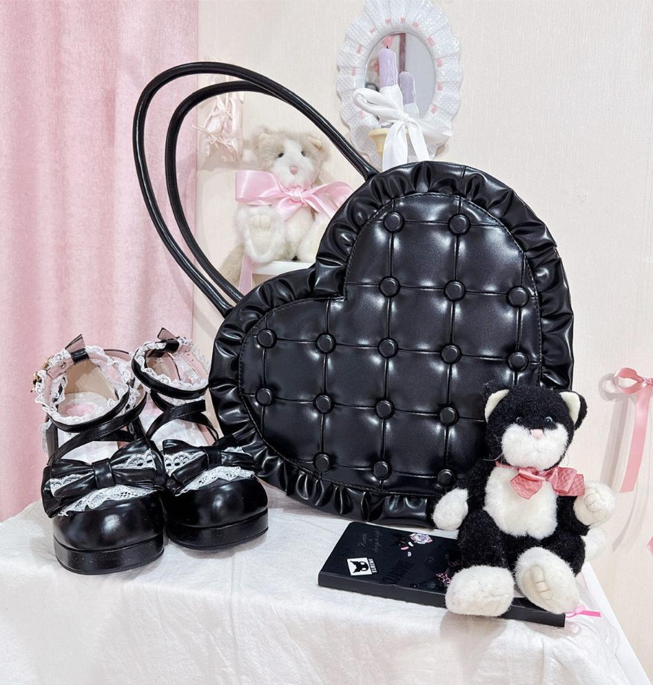 Black quilted handbag, black shoes with white bows, and a small black and white teddy bear on a light pink background.