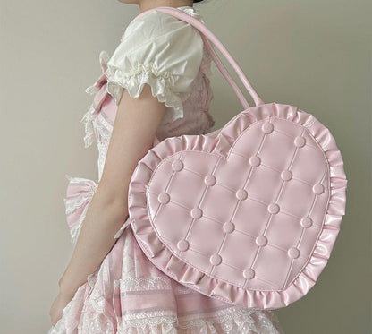 Person wearing a pink dress holding a matching pink heart-shaped bag against a neutral background