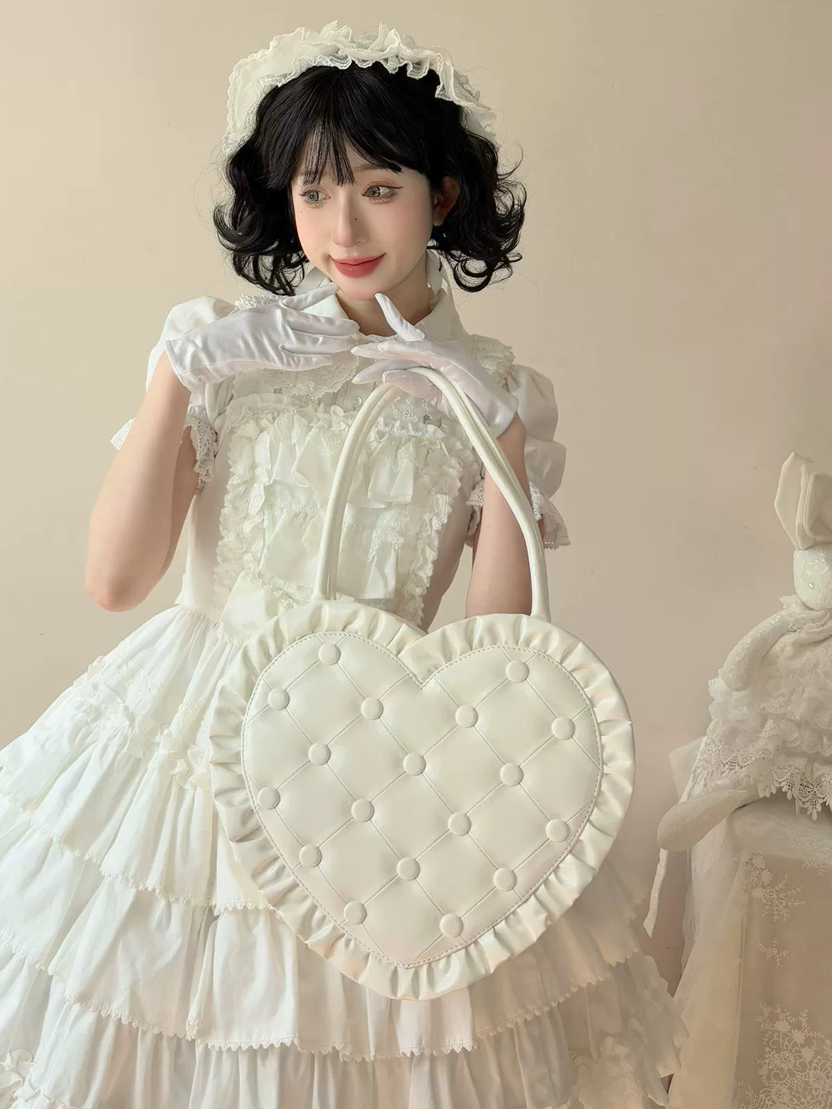 Woman in a white dress holding a polka dot bag against a neutral background