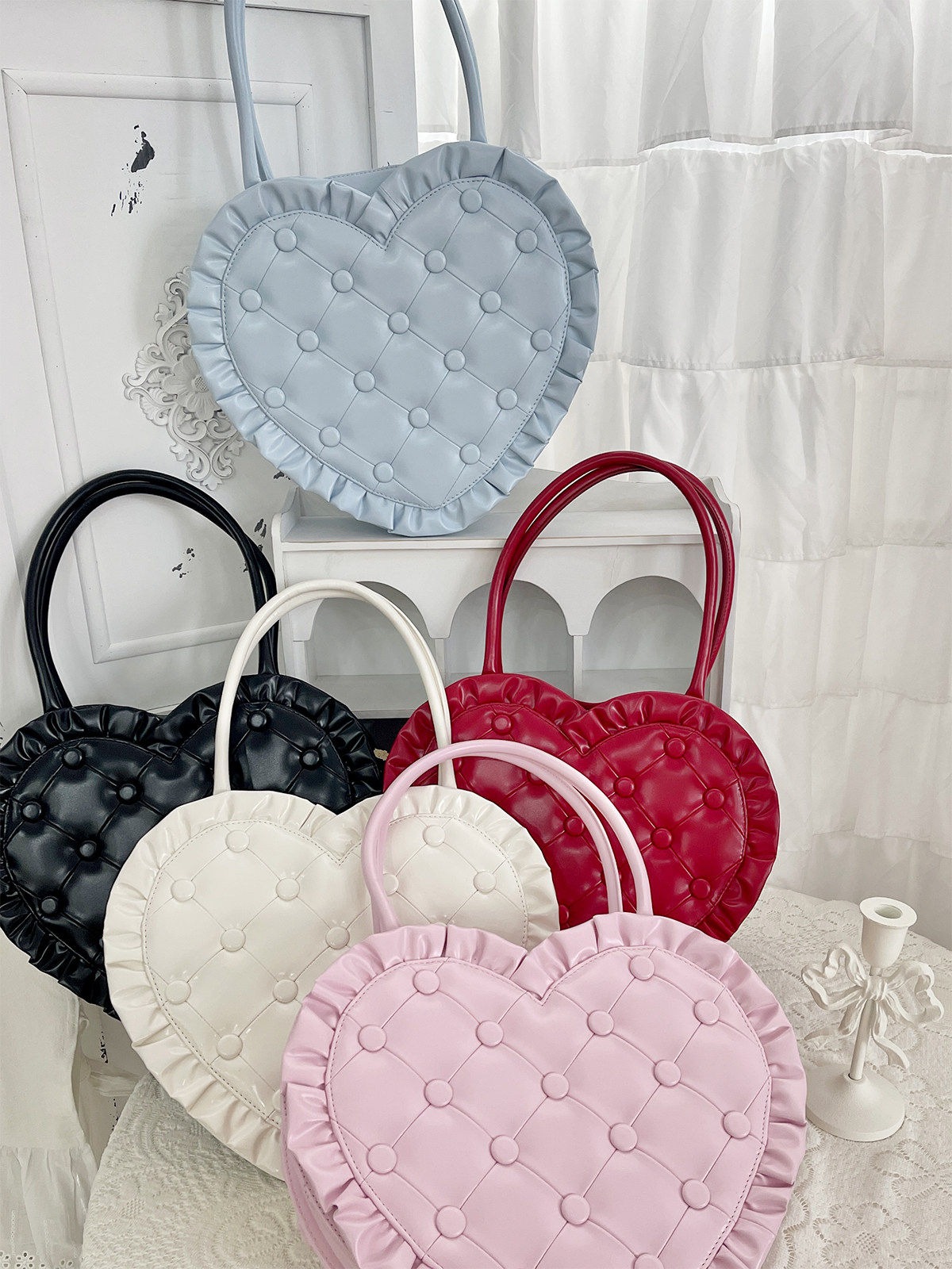 Set of heart-shaped handbags in various colors on a white surface.