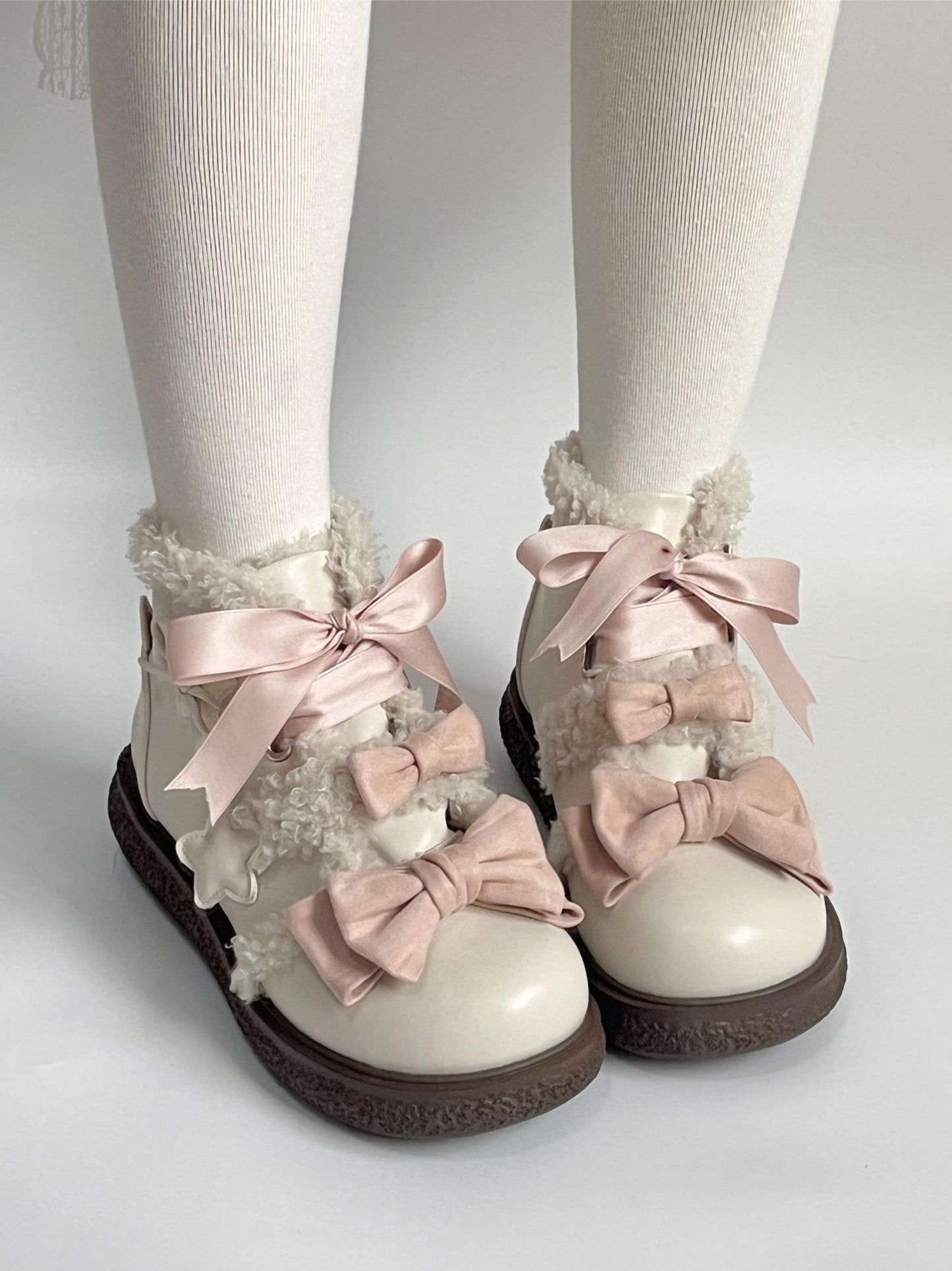 lolita style winter shoes with pink bows and white tights on a light gray background