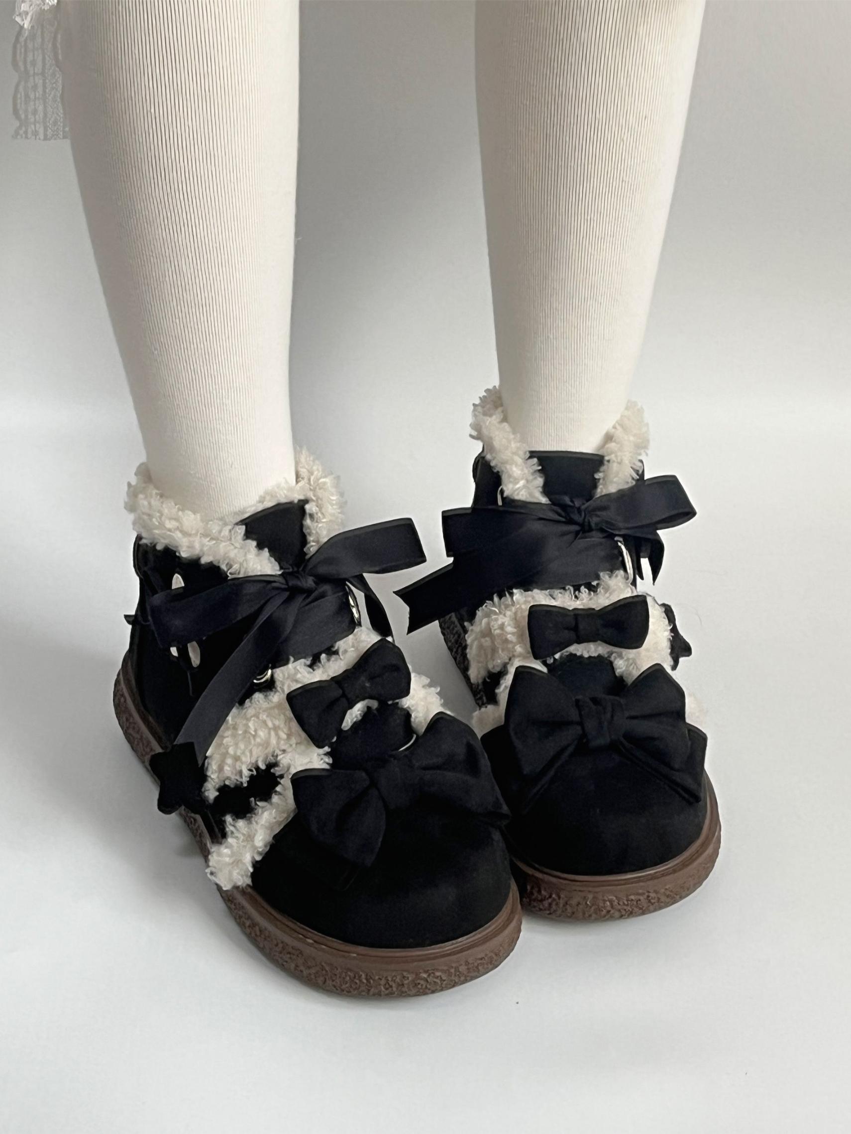 Black lolita style boots with bows worn with white tights on a light gray background