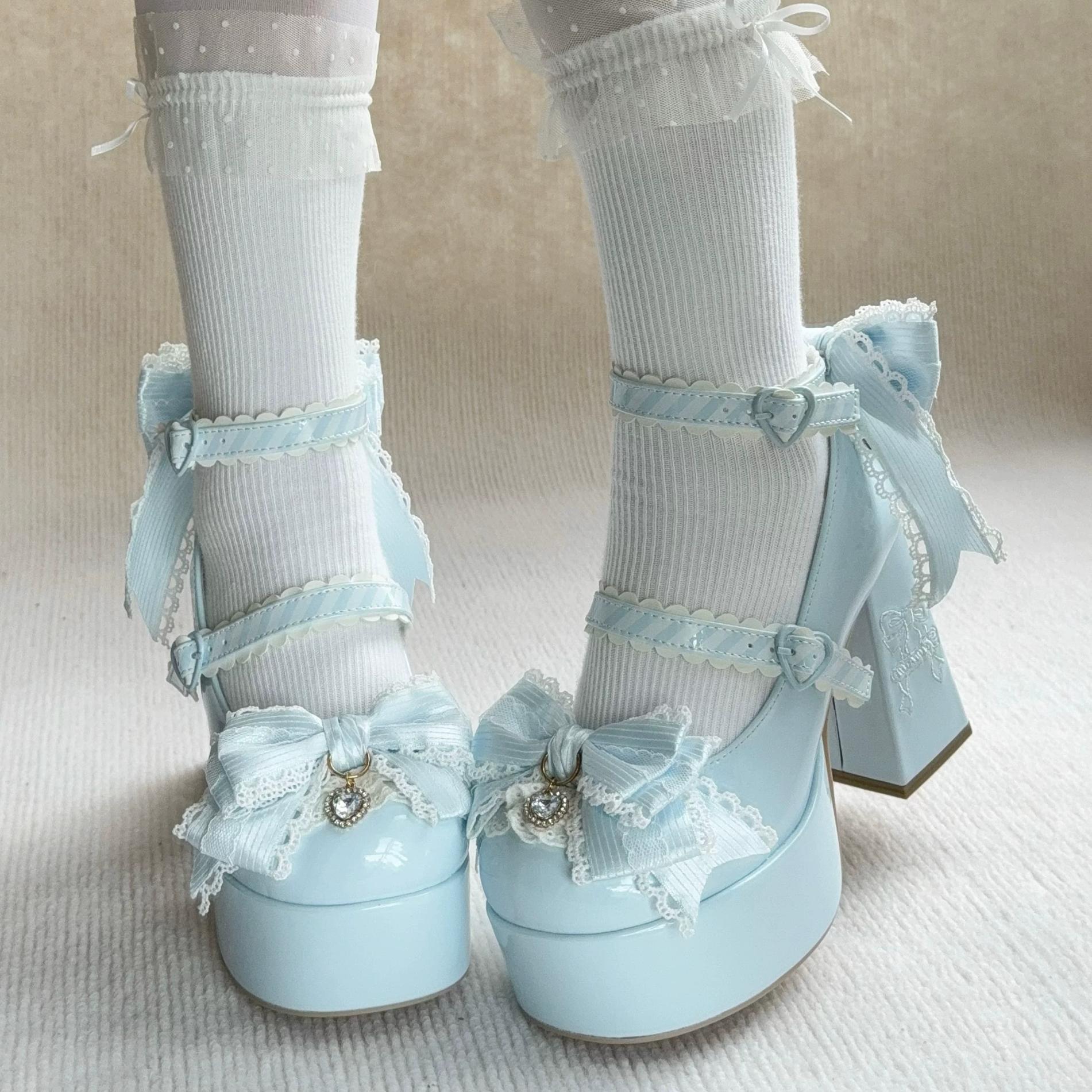 Light blue high-heeled shoes with decorative bows and ribbons worn with white socks on a neutral background.