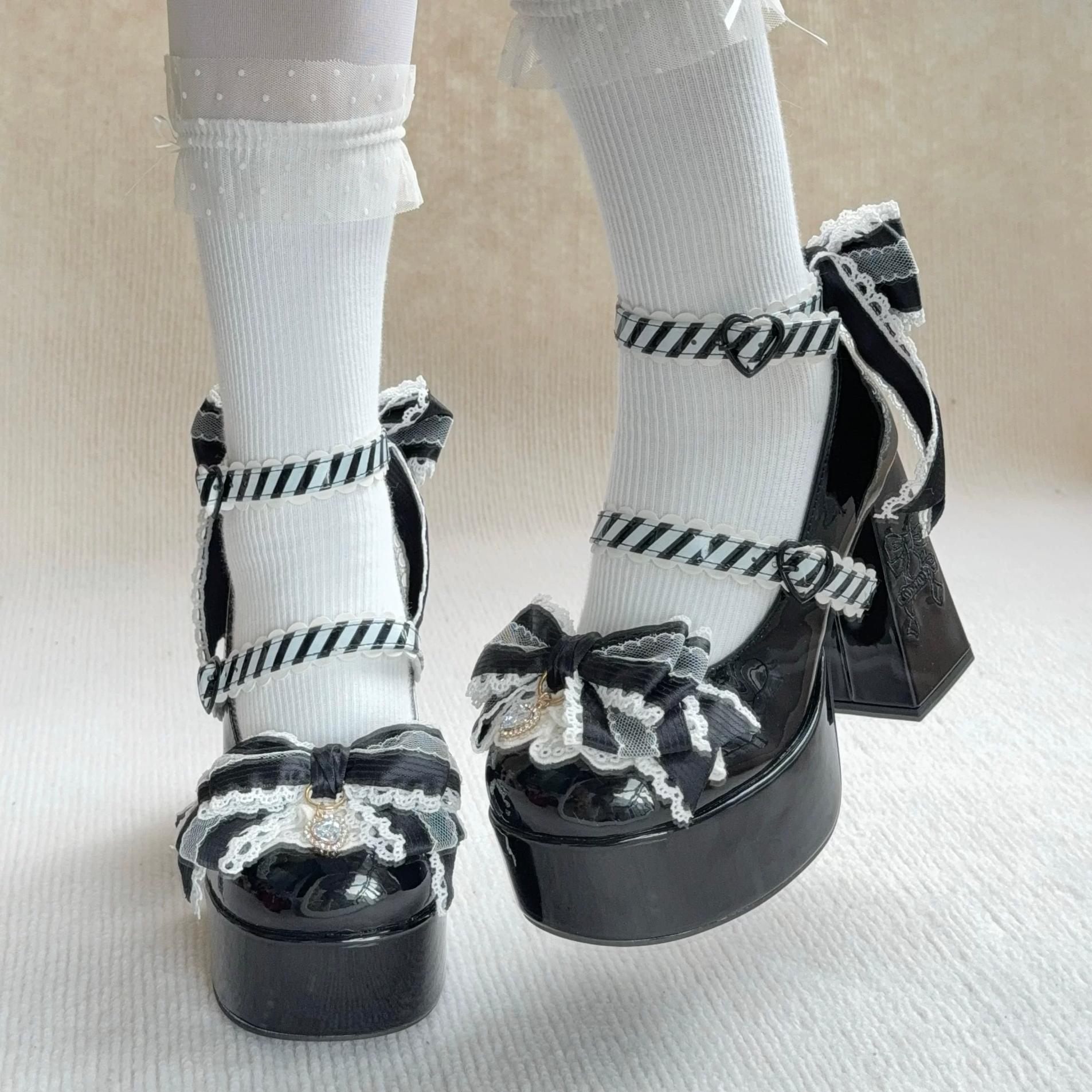 Black platform shoes with decorative bows worn with white socks on a neutral background