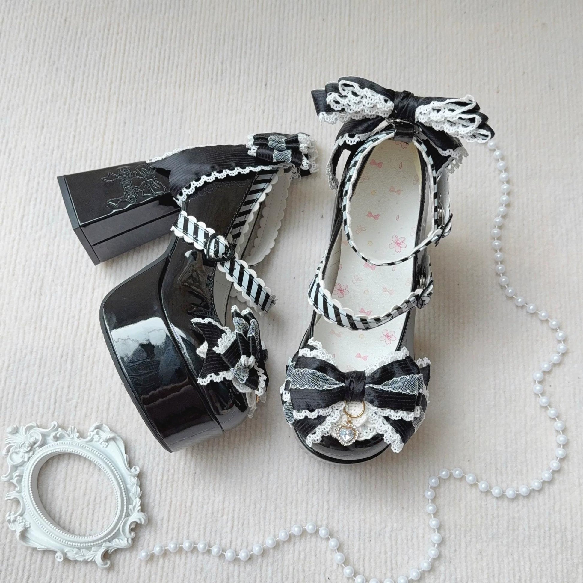 Black high-heeled shoes with decorative bows and ribbons on a light background