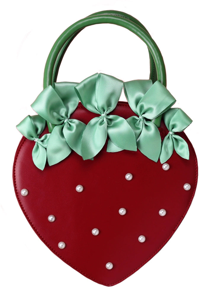 Strawberry-shaped handbag with green bows and pearl details on a white background