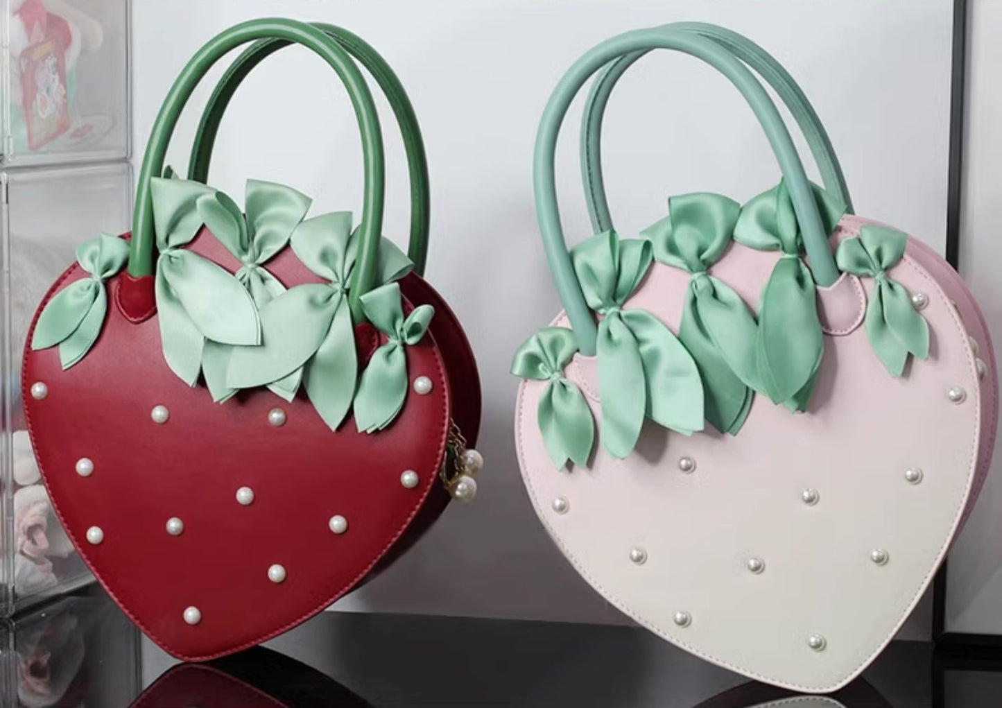 Two heart-shaped bags, one red and one pink, with green bows on a white background.
