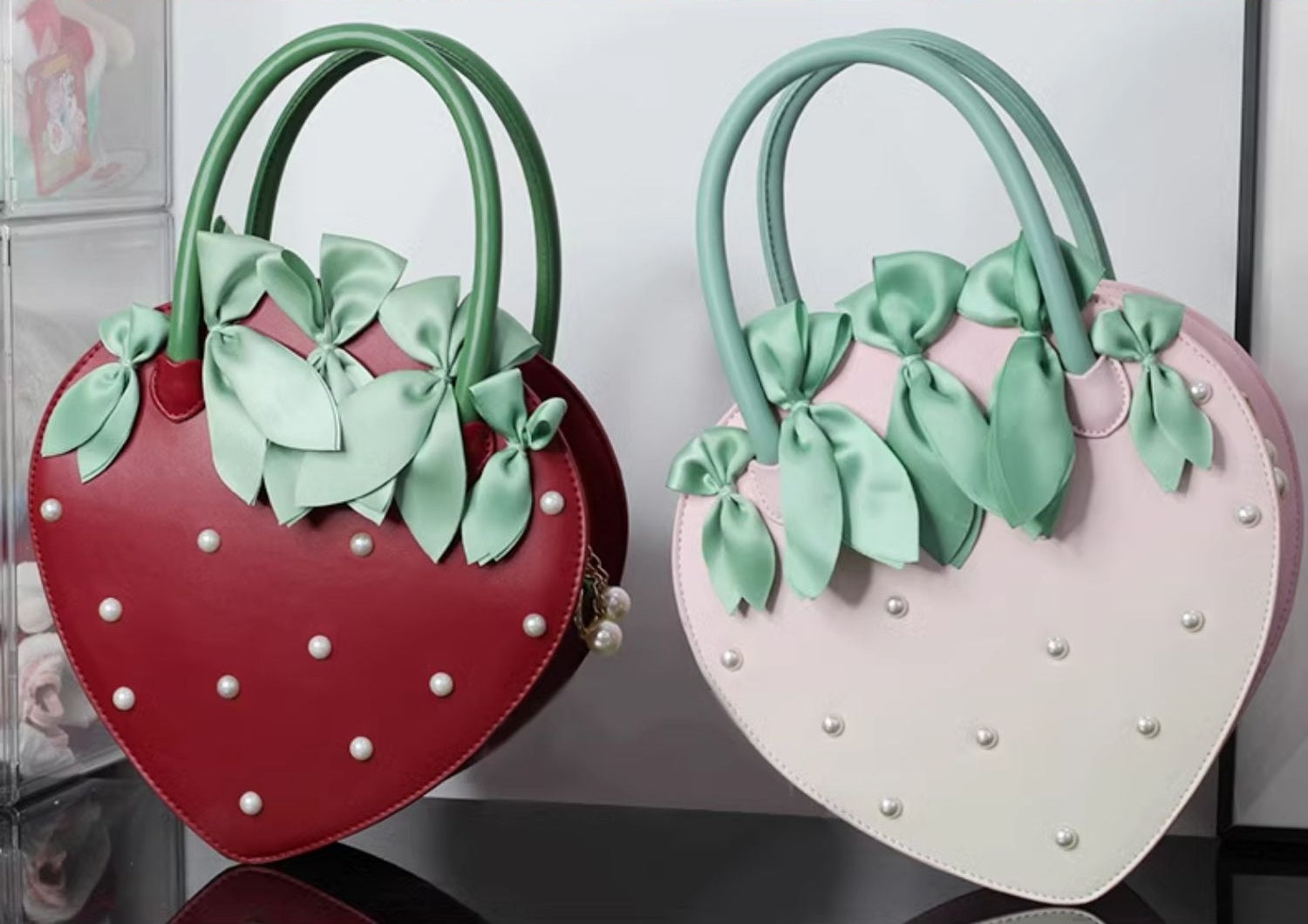 Two heart-shaped bags, one red and one pink, with green bows on a white background.