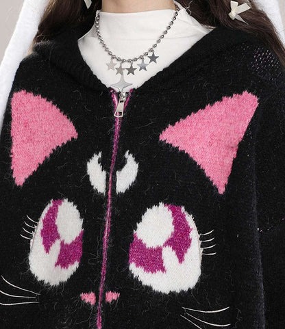 Black cat-themed sweater with pink and white details worn by a person.