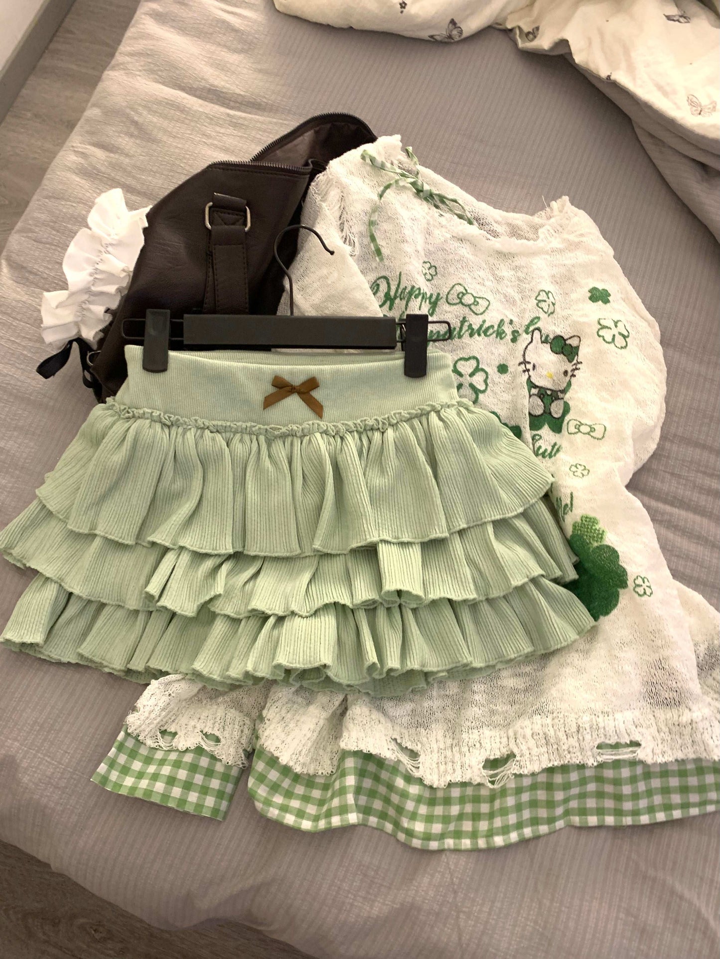 Green tiered skirt with white lace and black bag on a gray surface