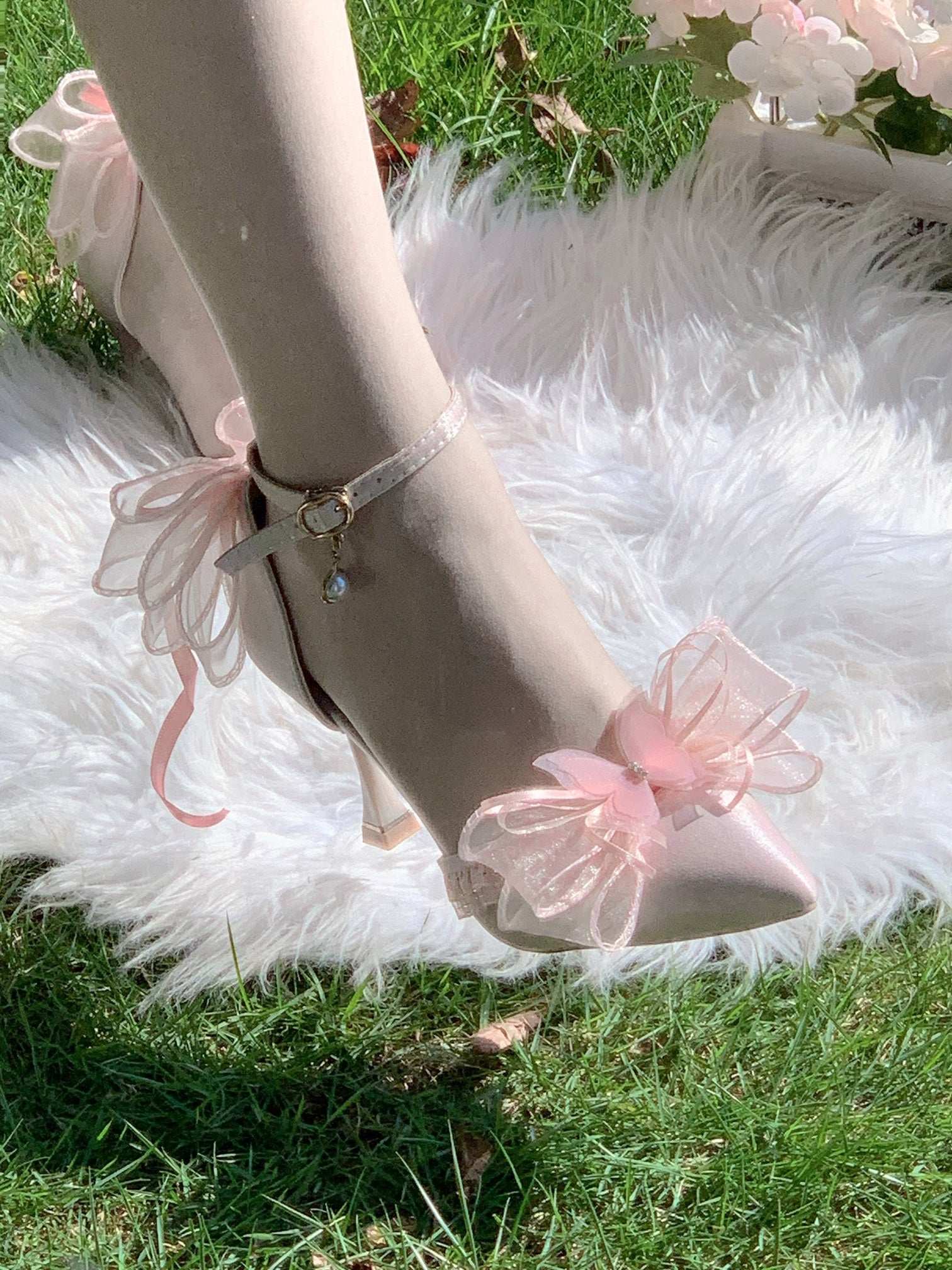 High-heeled shoes with pink bow details on a fluffy white rug.