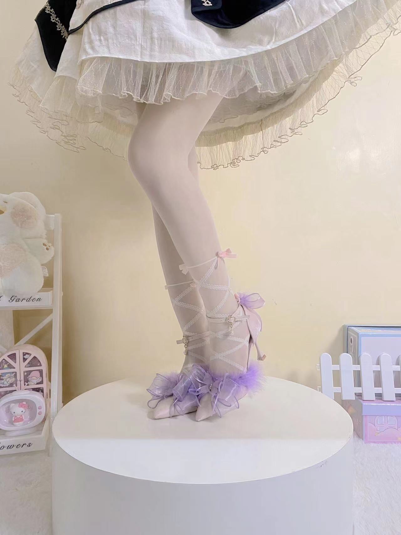 Person wearing a white dress with a sheer overlay and purple shoes on a white platform.