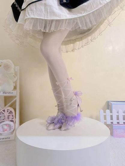 Person wearing a white dress with a sheer overlay and purple shoes on a white platform.