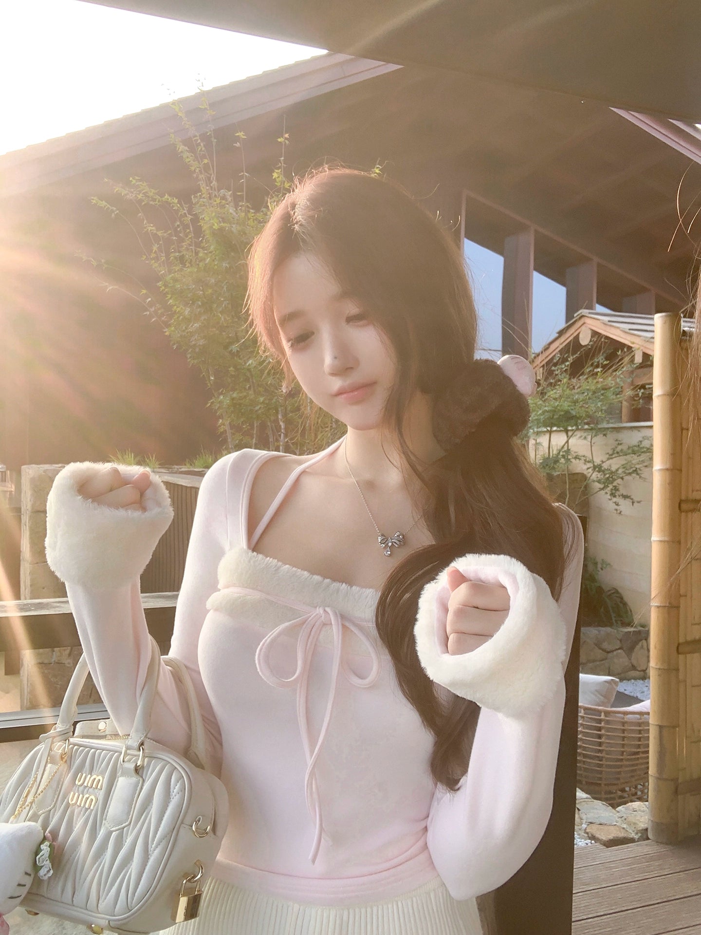 Woman in a light outfit with gloves holding a handbag outdoors.