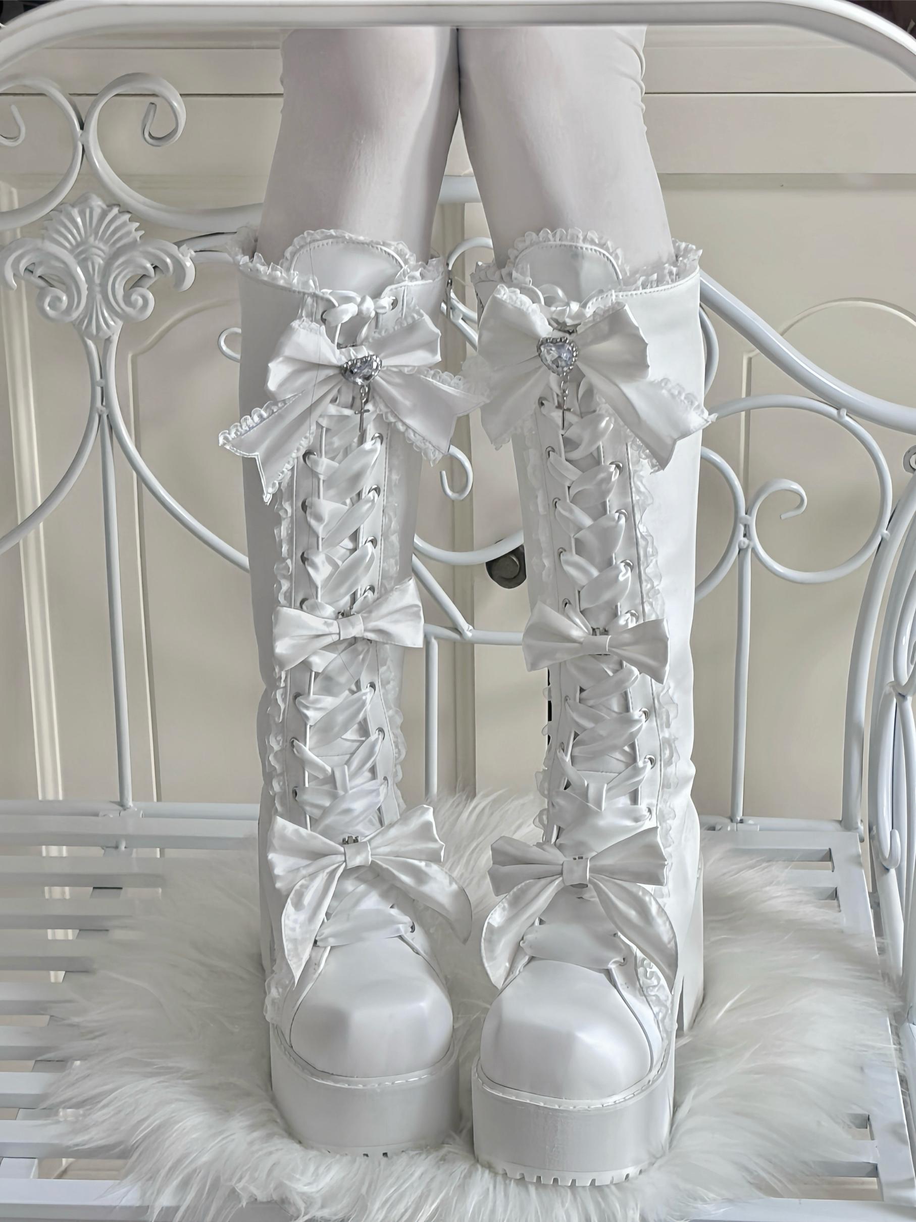White lace-up boots with decorative bows on a white background