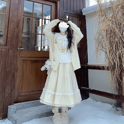 Person in a cream-colored outfit standing in front of a wooden door.