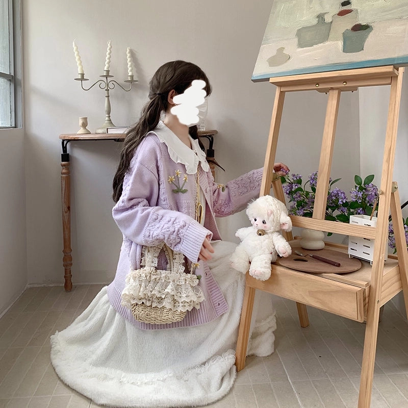 Person in a fall outfit with a teddy bear and an easel in a room setting.