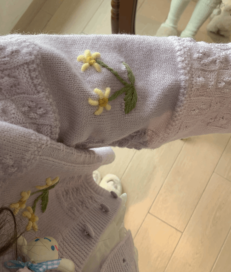 Close-up of a textured fabric with embroidered yellow flowers on a wooden floor.