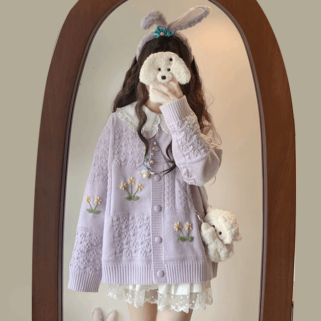 Person wearing a light purple cardigan with floral embroidery in front of a mirror.