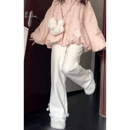 Person wearing a pink outfit with white pants and shoes, holding a white plush toy, standing in a doorway.