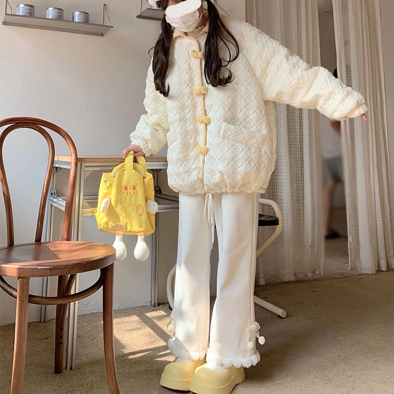 Person wearing a white quilted jacket and pants with a yellow bag indoors.